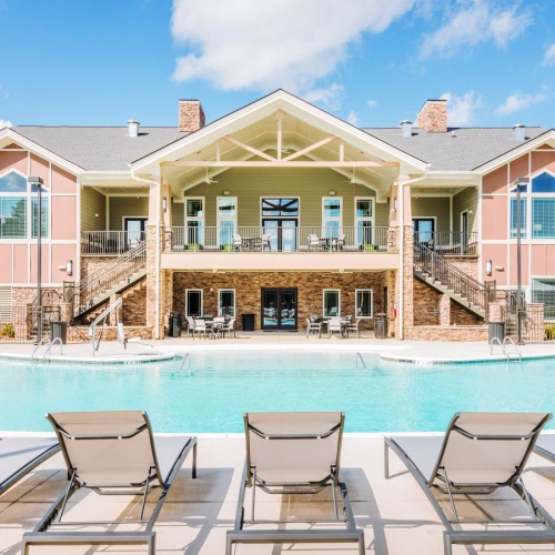 Relax and unwind poolside a pool with chairs around it